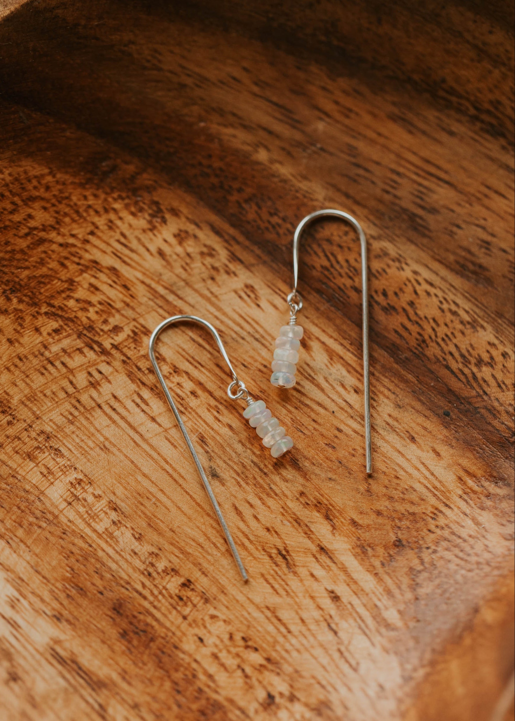 Silver earrings with clear stones on a wooden surface